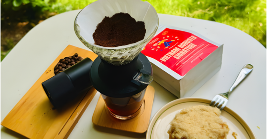 Vietnamese Robusta coffee setup with coffee beans, grinder, pour over, and pastry on outdoor table